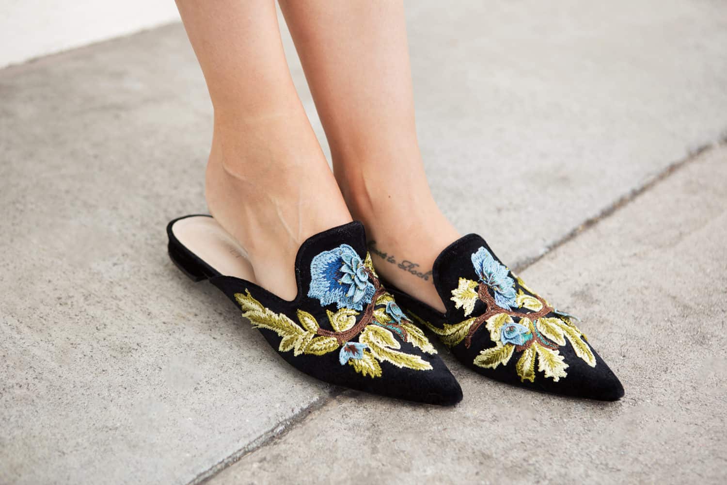 woman wearing black embroidered mules