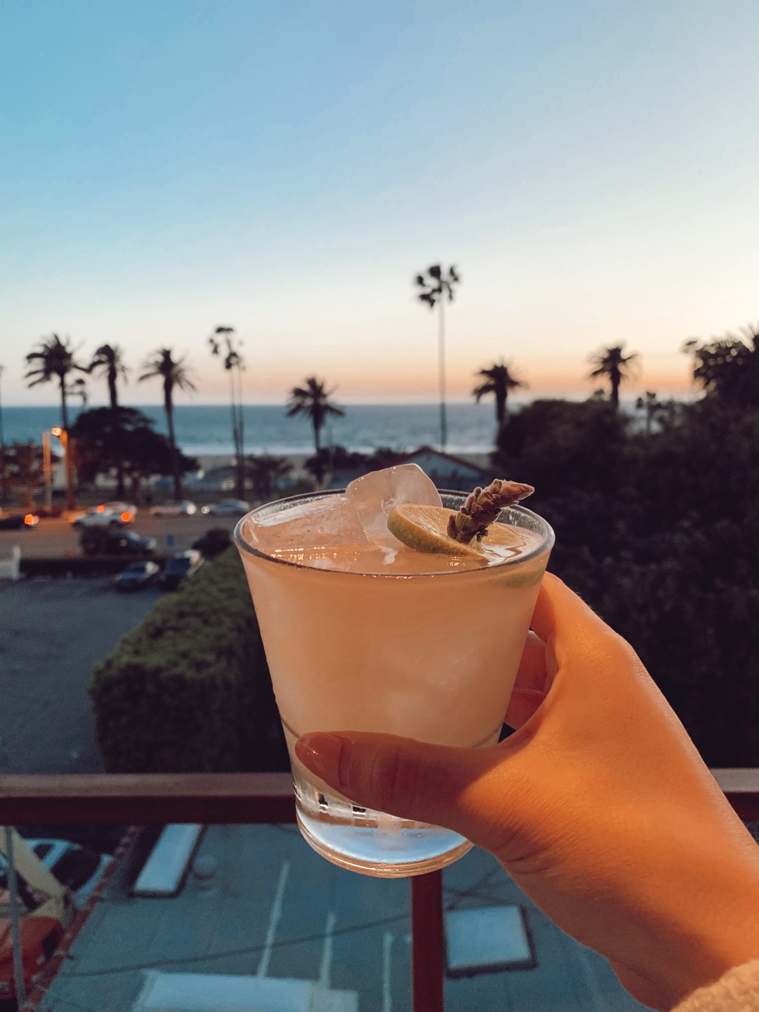 woman holding a drink with a view from the PATIOS AND ROOFTOPS IN LA